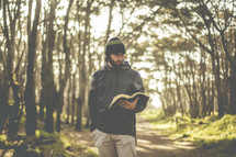 a man in a forest reading a Bible 