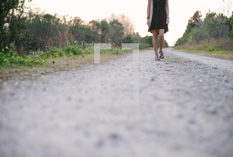 young woman walking down a gravel road 