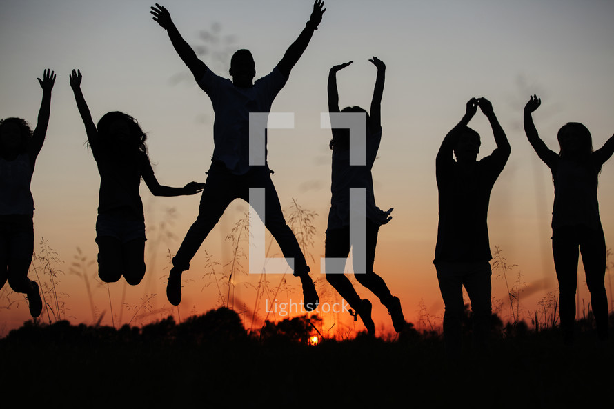 silhouettes of people jumping at sunset.