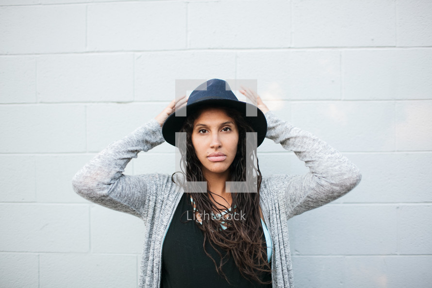 woman in a hat with her hands on her head 