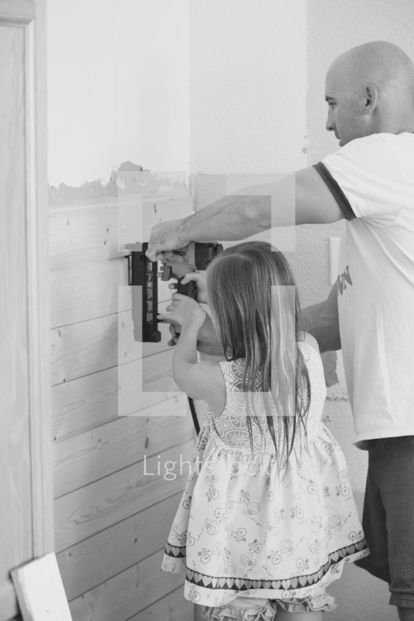 father and daughter using a nail gun to put up shiplap 