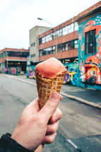 a man holding an ice cream cone in a city 