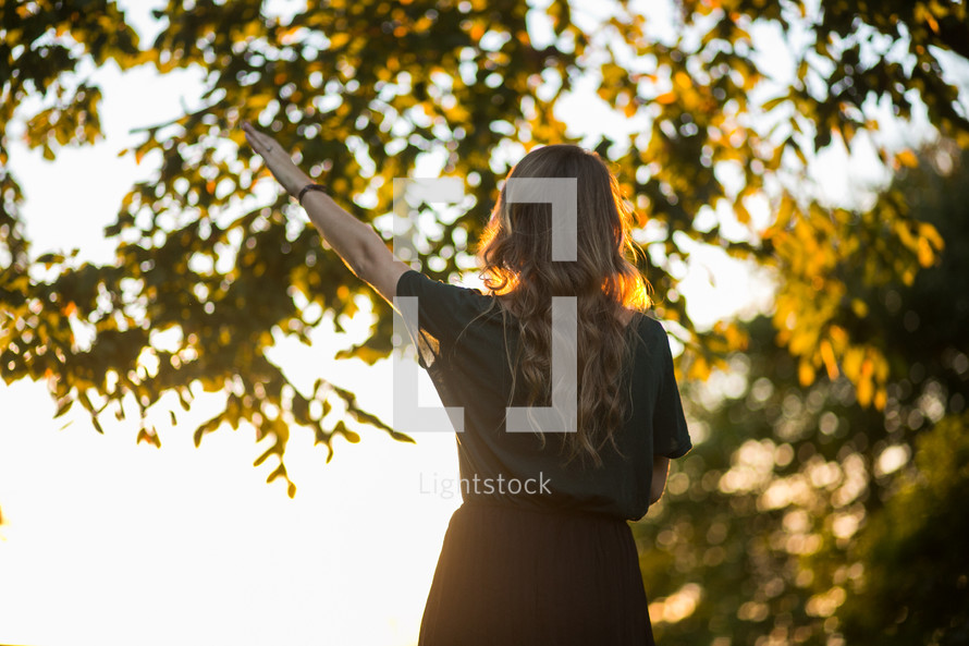 a woman with raised hand standing outdoors 