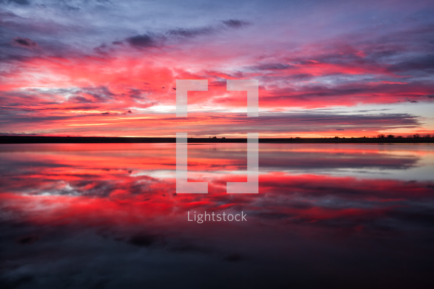 reflection of a pink and purple sky over water 