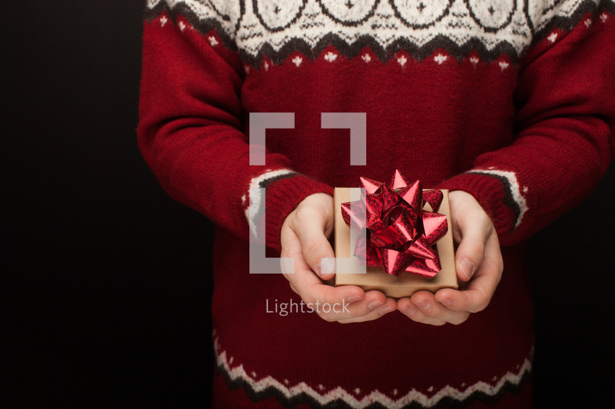 a man in a sweater holding a Christmas gift box 