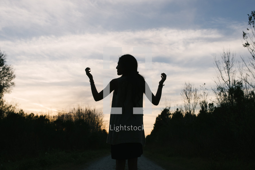 silhouette of a young woman with raised hands 