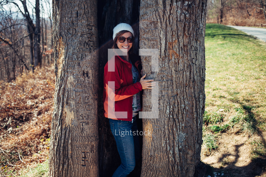 a woman hiding in a tree trunk 