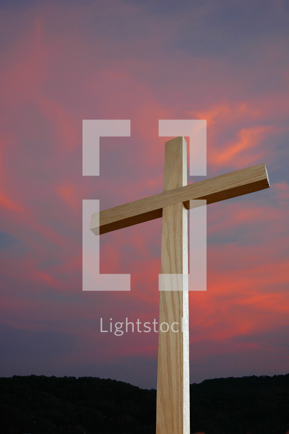 wood cross against a pink and purple sky 