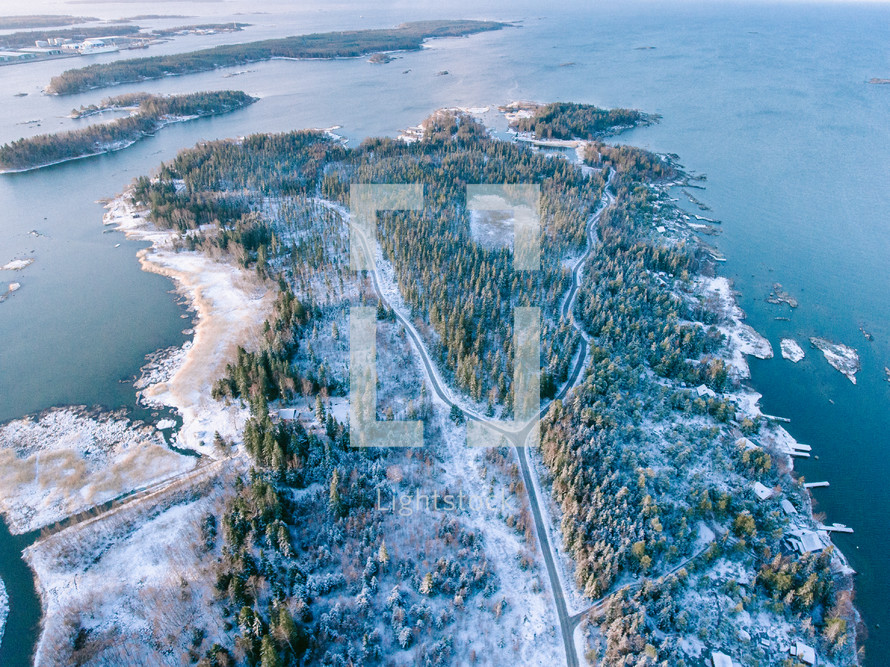 aerial view over a snowy highway along a shoreline 