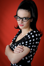 Woman in cateye glasses with arms folded.
