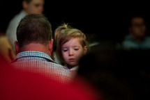 a father holding his toddler daughter at church 