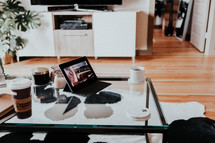 coffee cups and laptop computer on a coffee table 