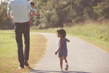 father and daughters walking down a path