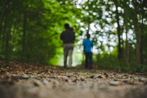 father and children walking on a path in the woods 