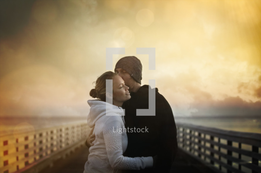 a couple kissing on a pier 