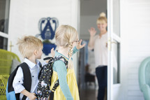 mother waving goodbye to her kids as the leave for school