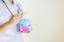 healthcare worker holding a piggy bank 