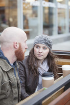 Couple sitting outside with coffee having a serious conversation.