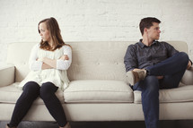 Estranged couple sitting on a couch after an argument.