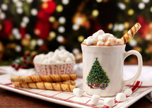 Hot Chocolate in a Christmas Cup Piled High with Marshmallows with Christmas Tree in Background