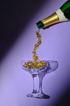 Champagne bottle with gold glitter flowing into champagne glass