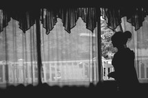 a young woman looking out from behind the curtain
