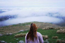 a woman looking out at clouds over a valley