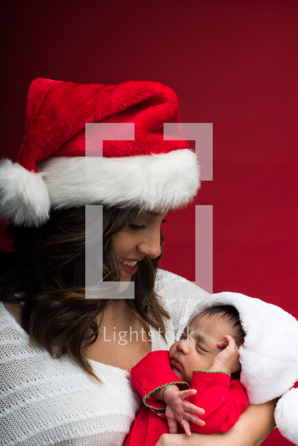 A mother in a Santa hat cradling a newborn 