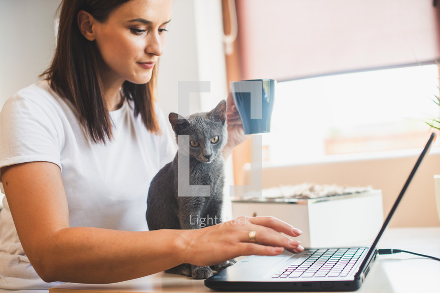 a woman at her laptop with her pet cat 