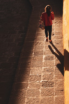 a girl walking in warm sunlight on a sidewalk 
