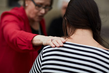 elderly woman lying her hands on a young woman in prayer 