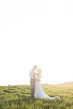 bride and groom hugging outdoors under intense sunlight 