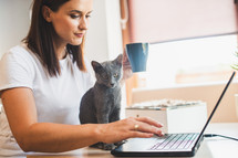 a woman at her laptop with her pet cat 