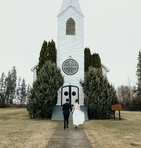 Husband and wife walking towards a small church.