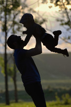 silhouette of a father picking up his son 