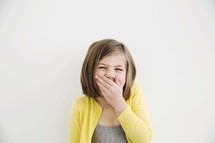 little girl covering her mouth while laughing. 