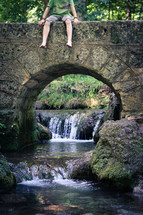 man's feet dangling off a bridge 