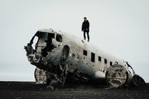 a man standing on a wreckage of an airplane crash site 