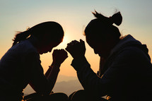 Silhouette of two woman praying. 