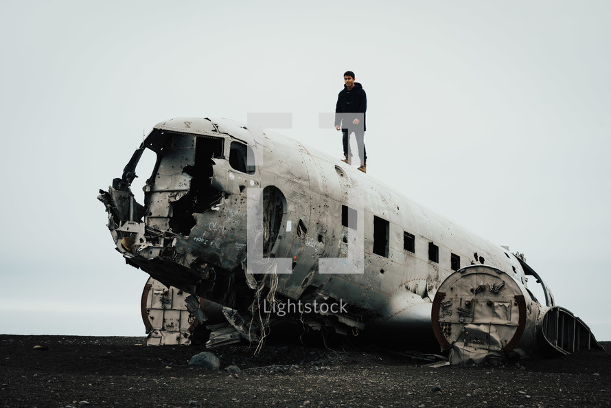 a man standing on a wreckage of an airplane crash site 
