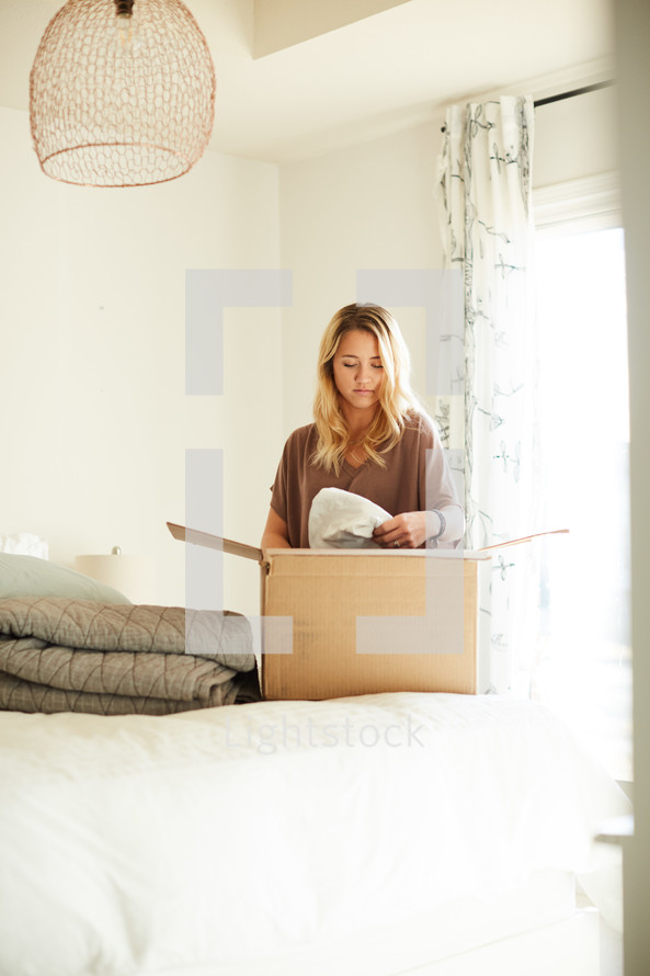 a young woman packing a moving box 
