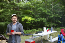 a man near a picnic table at a campsite 