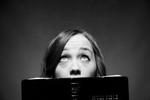 woman reading a Bible and looking up to God