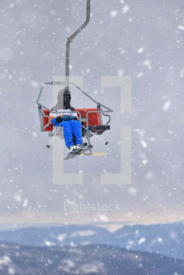 A Young Skier Enjoying the Ski Lift Amidst Falling Snow