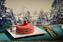 Meat patties with a Christmas ornament on a plate with Christmas tree background
