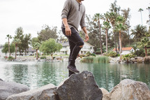 a man stepping onto rocks along a waterway 