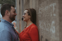 a couple standing together leaning against a wall 