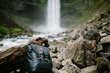 a backpack on rocks near a waterfall