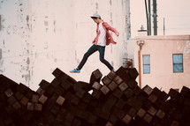a boy walking over a pile of lumber 