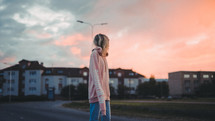 a woman walking down a street at sunset